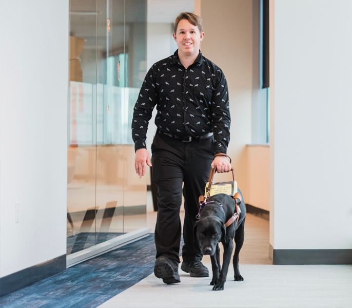Vision impaired man walking with his seeing eye dog