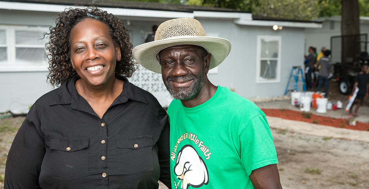 Happy homeowners shown smiling after a home rebuild