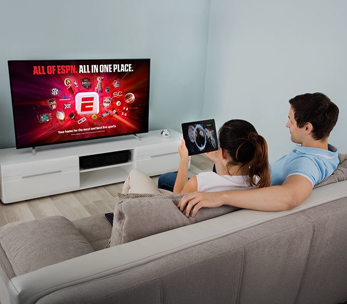 A couple watching ESPN and Hulu content on a TV and tablet