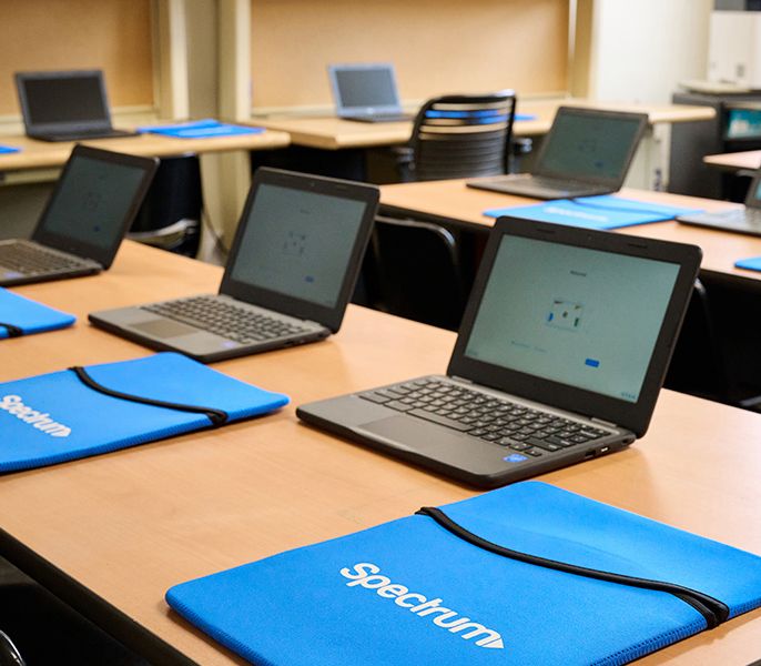 Laptops sitting in an empty computer lab with mousepad with Spectrum logo