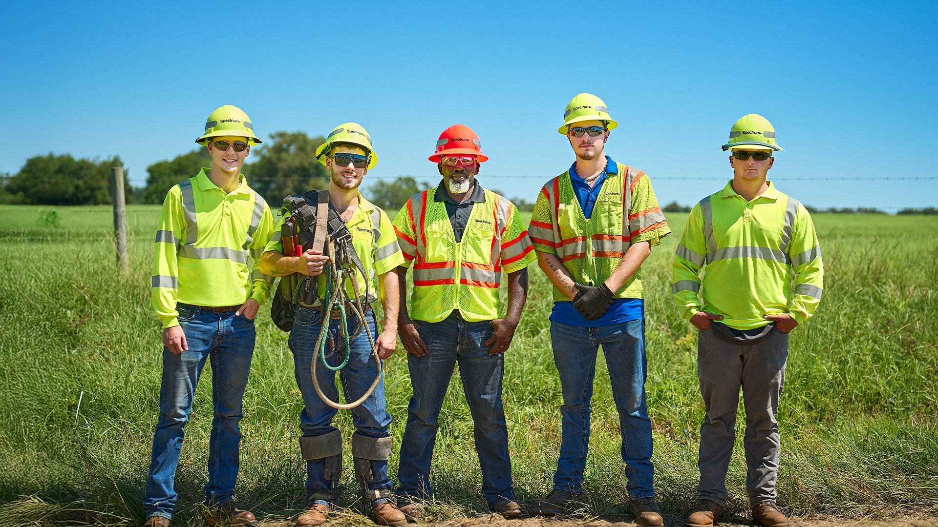 A group of five Spectrum field technicians posing in a row in a rural location