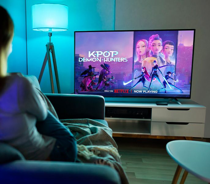 Family watching TV programming from their living room couch, viewed from behind
