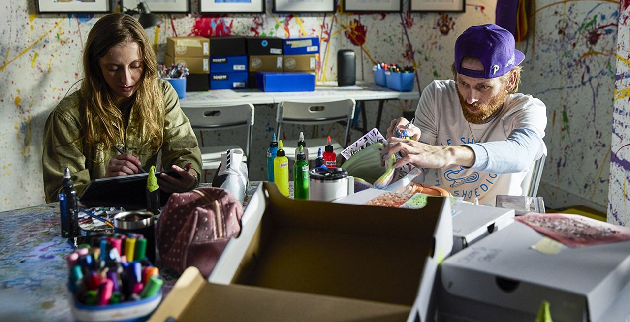 Man and woman small business owners creating custom designed sneakers in their shop