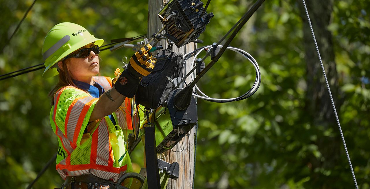 Spectrum technician on a ladder working on broadband infrastructure