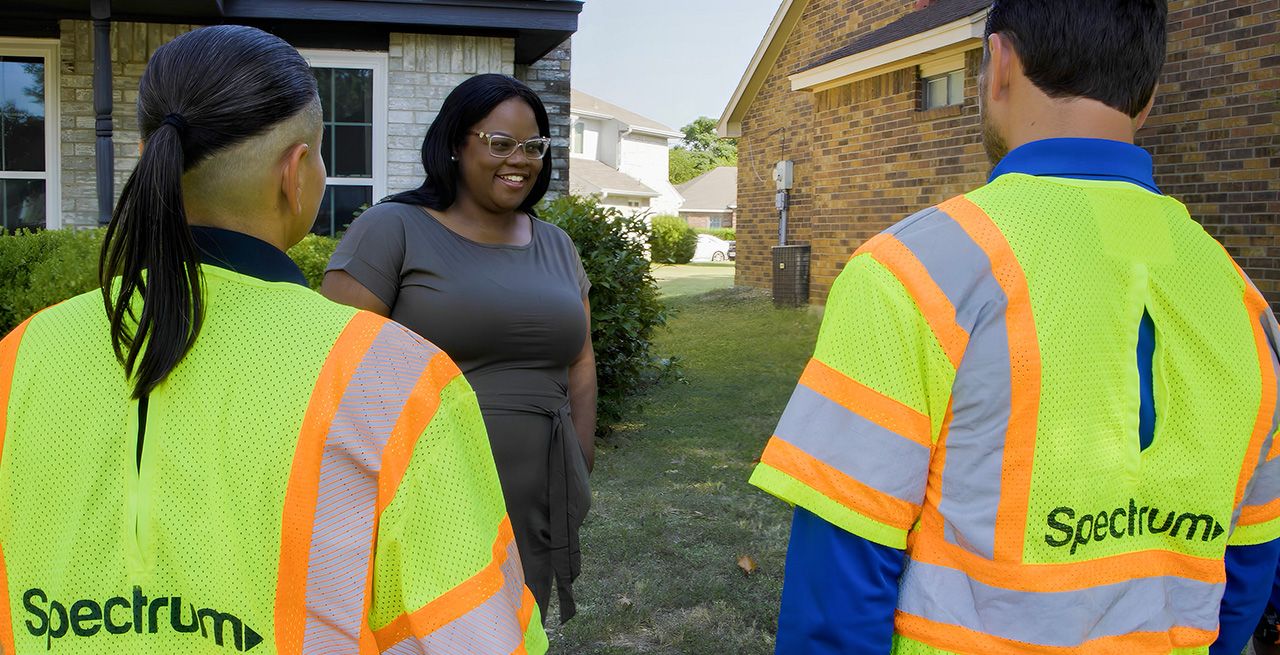 A Spectrum customer greeting technicians on her front yard