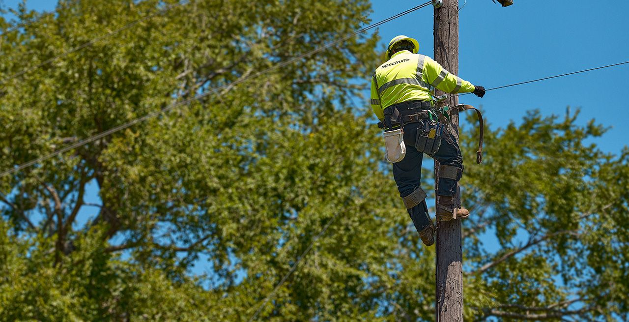A Spectrum field technician climbs a pole