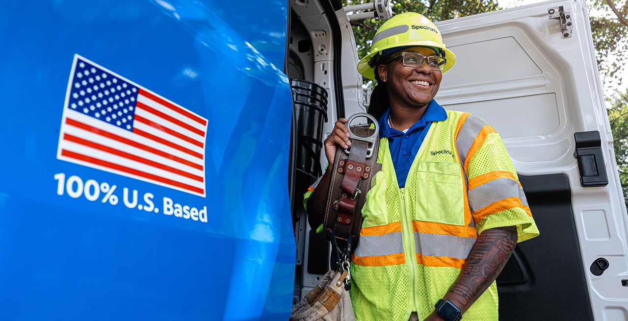 A Spectrum field technician standing at the back of his van, smiling