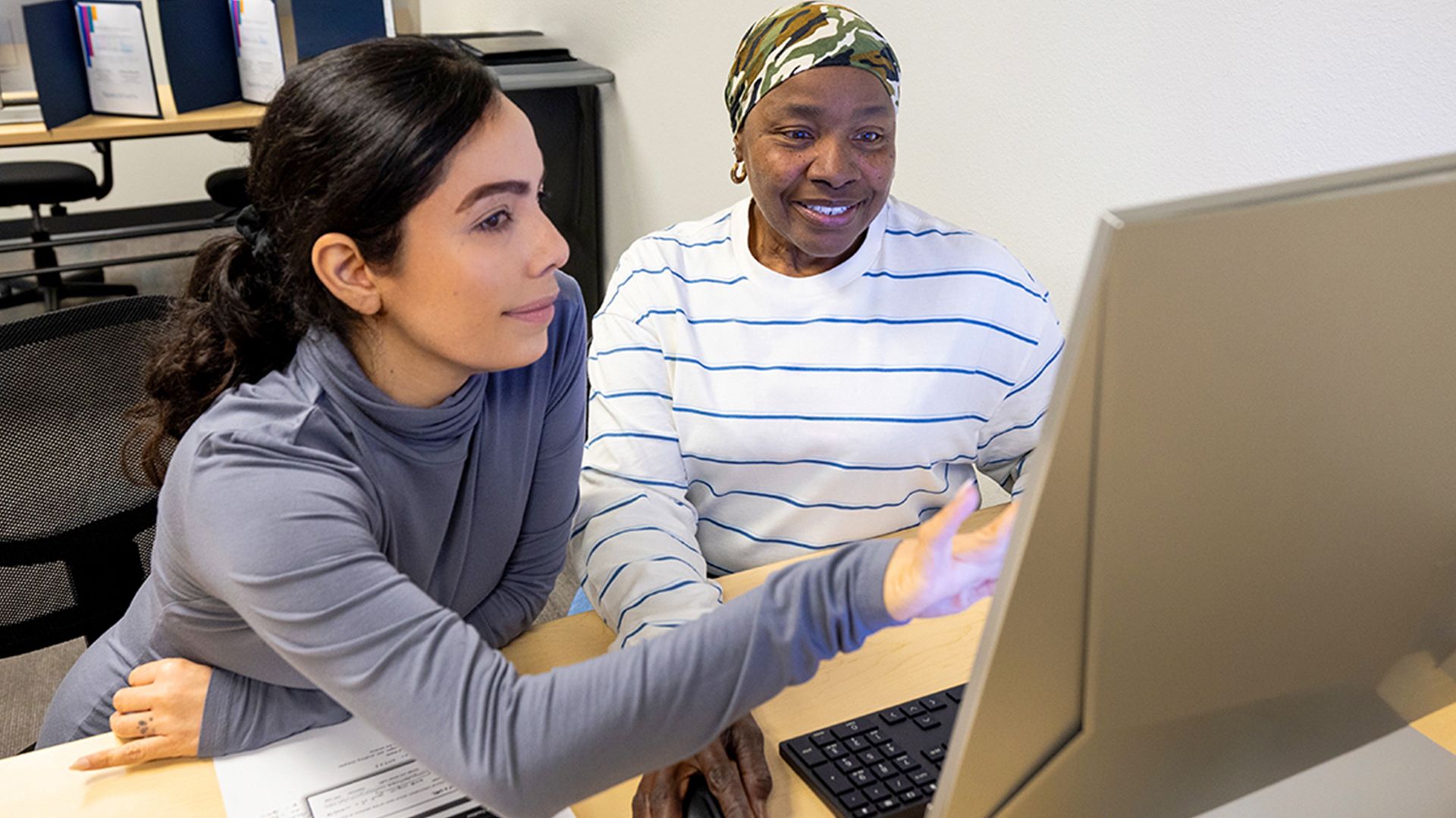 An adult getting instruction in a computer lab