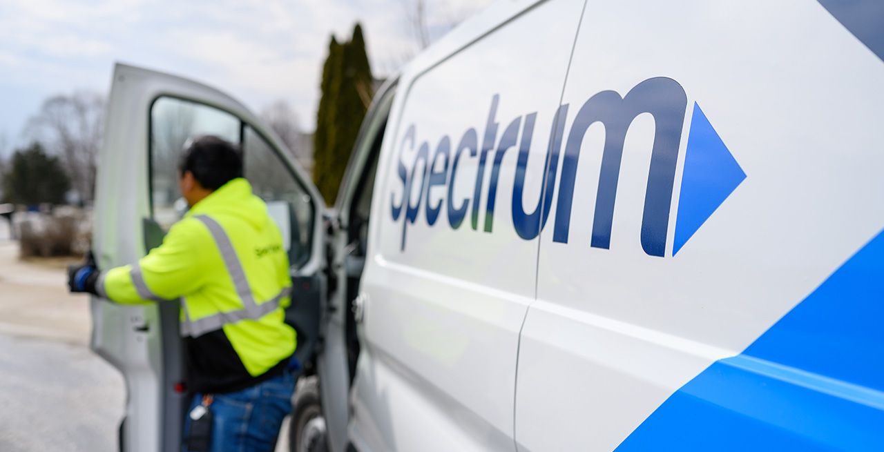 A Spectrum technician exits his van at a broadband expansion site