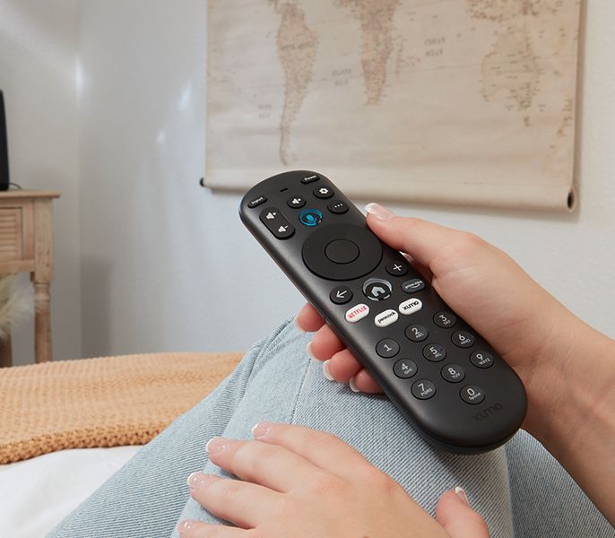 Someone holding a Xumo remote in a living room - hand and remote showing only