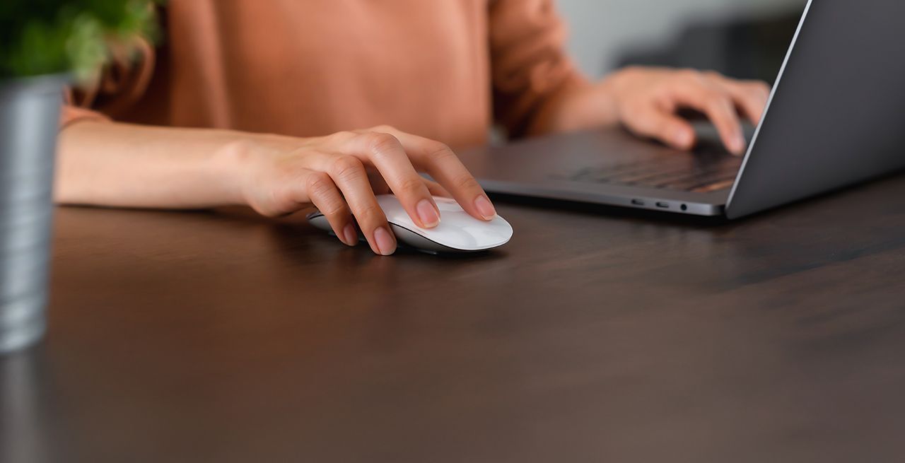 A journalist using a mouse and laptop but showing hands only
