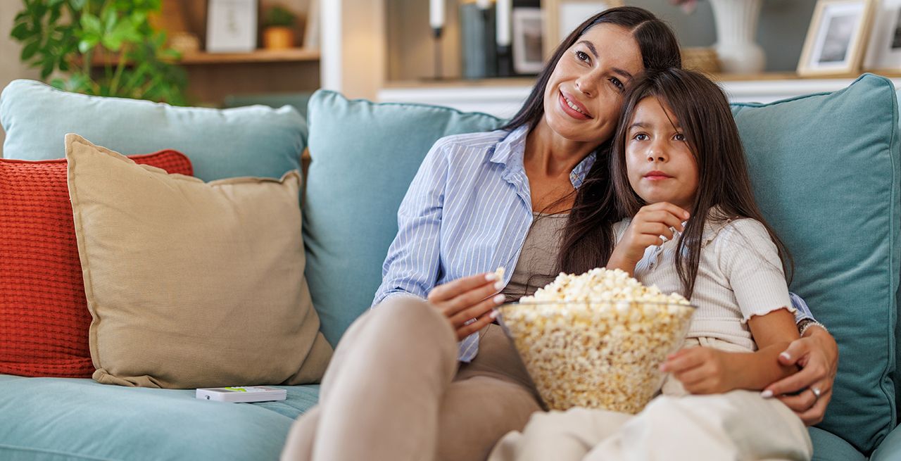 Mother and daughter watching a movie with popcorn.