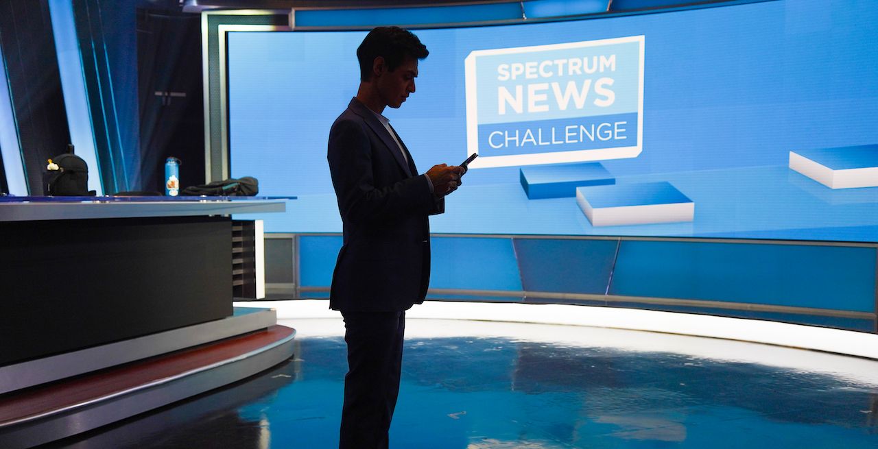 Spectrum News employee using cell phone in the studio, silhouetted