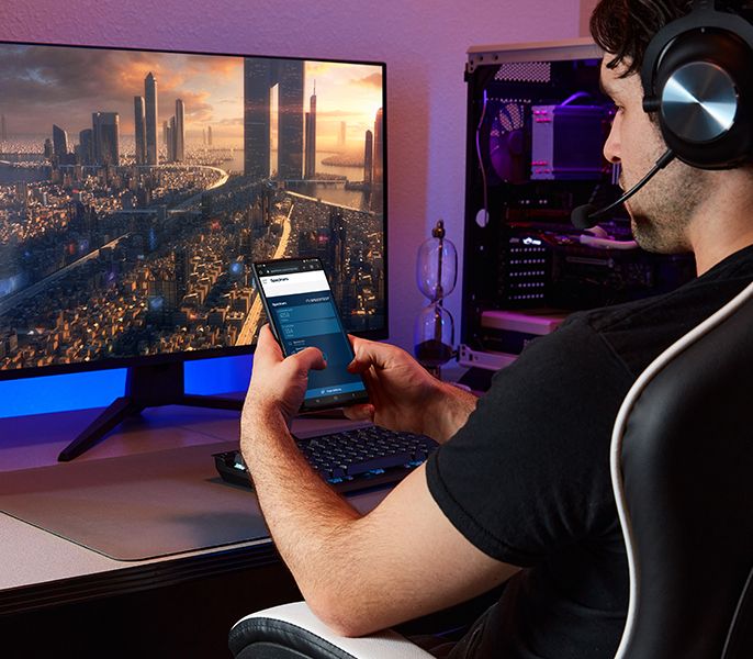 A Spectrum customer using his mobile phone while sitting at his desk with WiFi 7 router and desktop computer on the desk