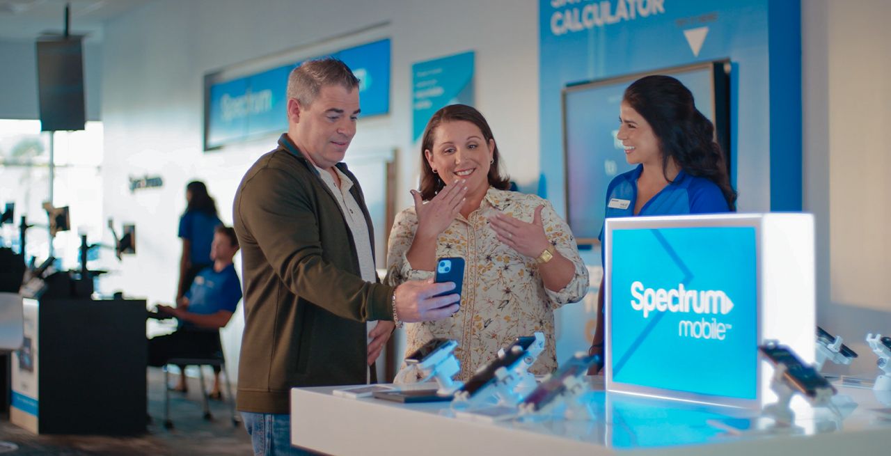 A pair of Spectrum customers using sign language to communicate in a Spectrum Mobile store, with a store rep helping them