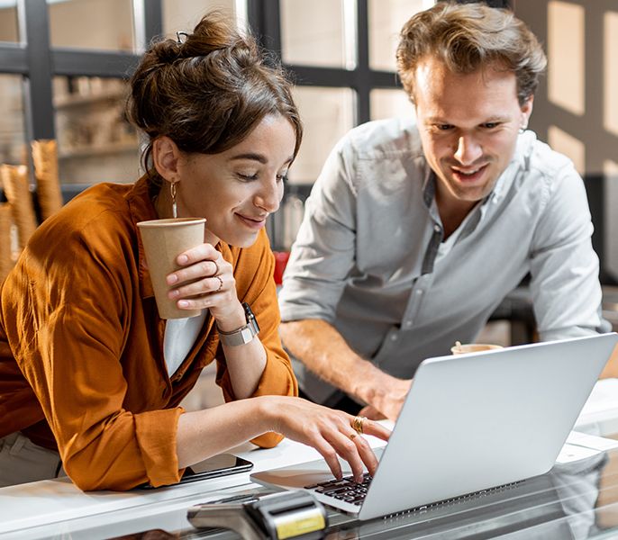 Man and woman looking at a laptop smiling in their place of business