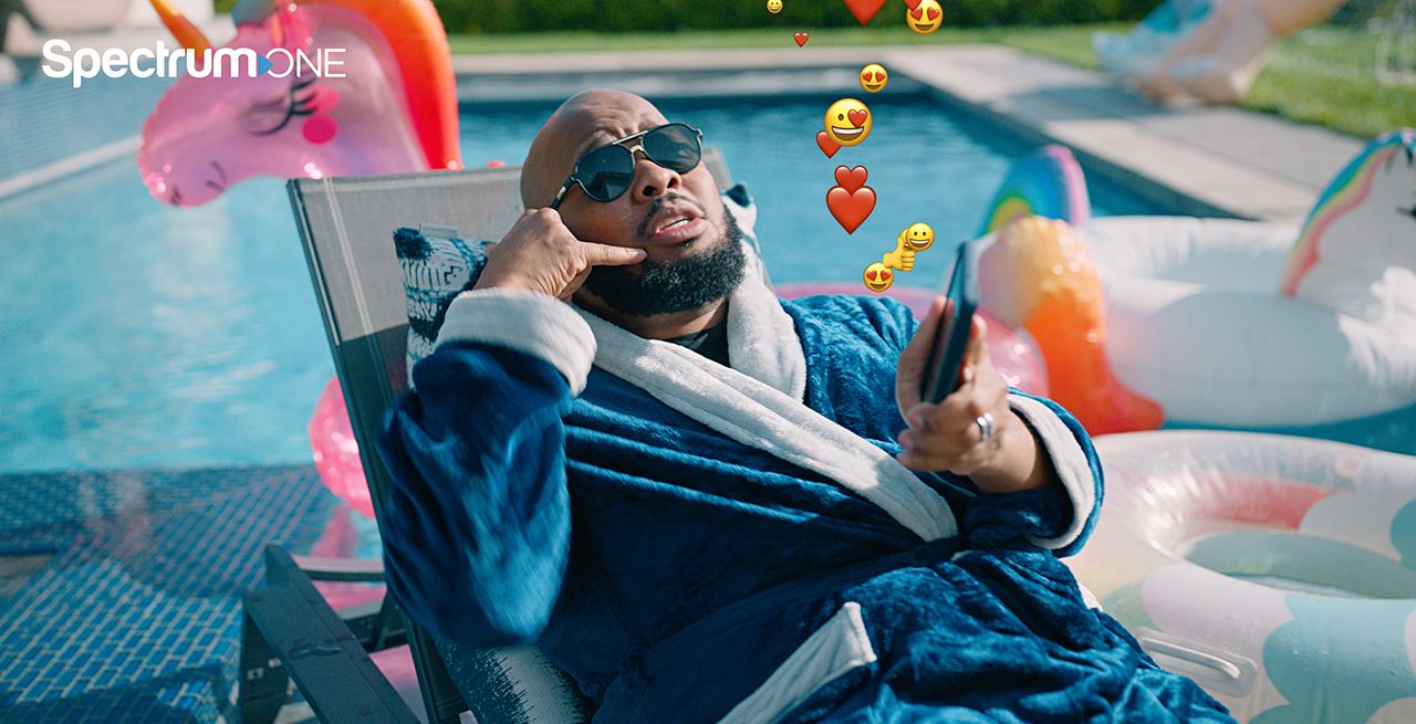 Man sitting by pool with his cell phone with emojis spilling from phone into the air