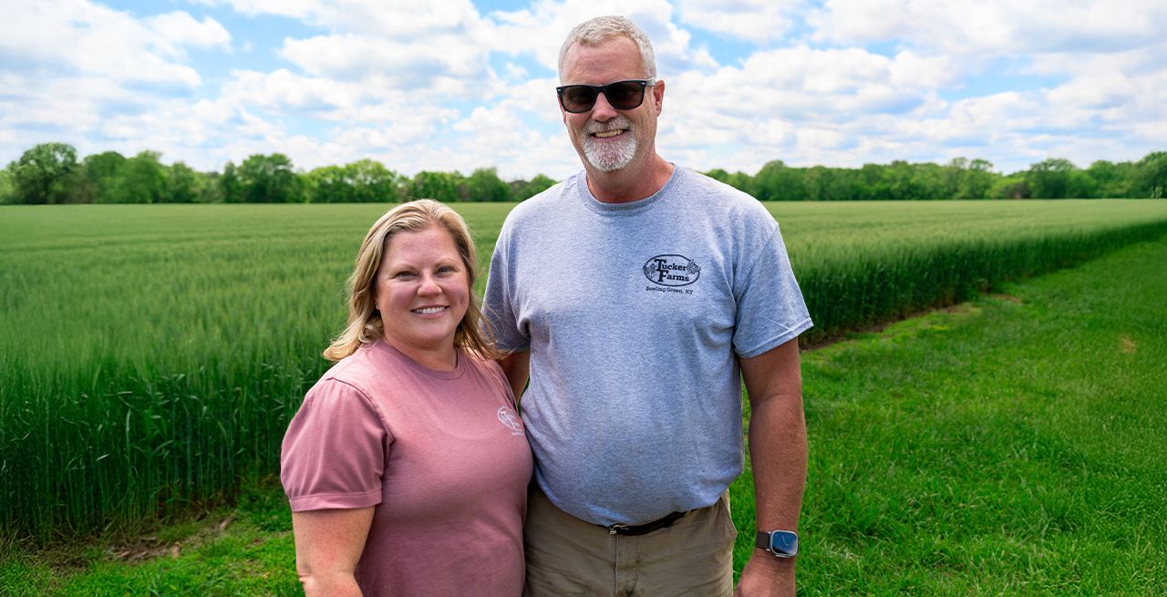 Jennifer Tucker and her husband pose next to a field of grain