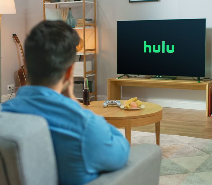 Someone watching TV in their living room with Hulu logo on the screen