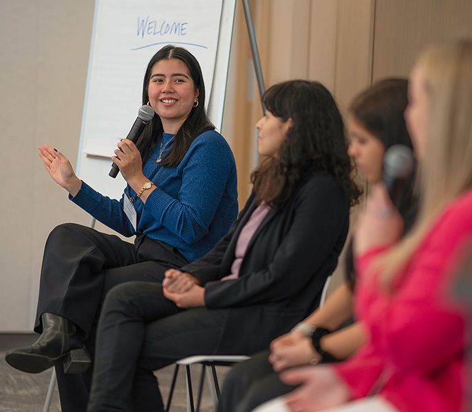 A Spectrum Scholar with a microphone sitting in a row with other scholars