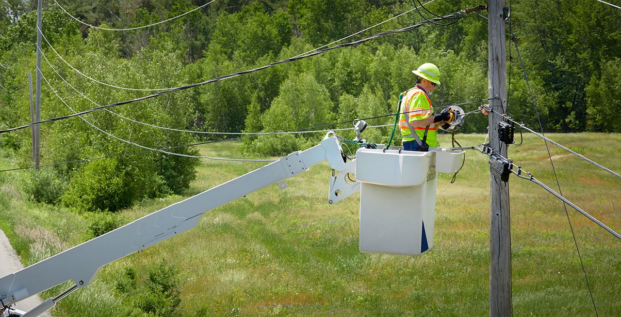 Spectrum technician using a lasher to attach cabling to a utility pole