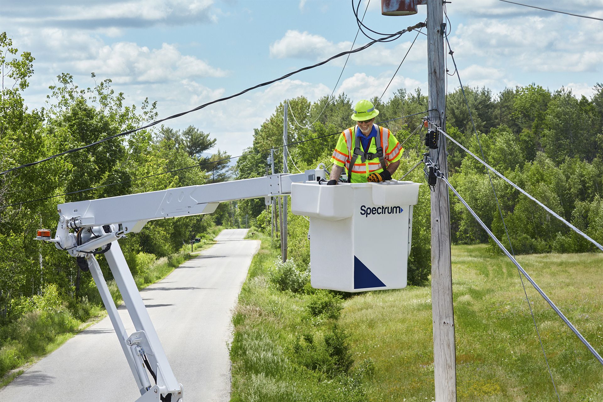 A Spectrum technician in a bucket working on broadband infrastructure