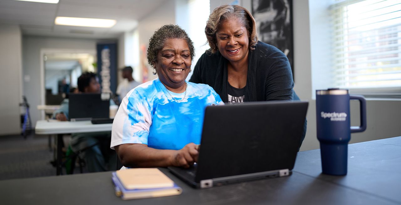 A female adult student getting training from a female instructor in a computer lab
