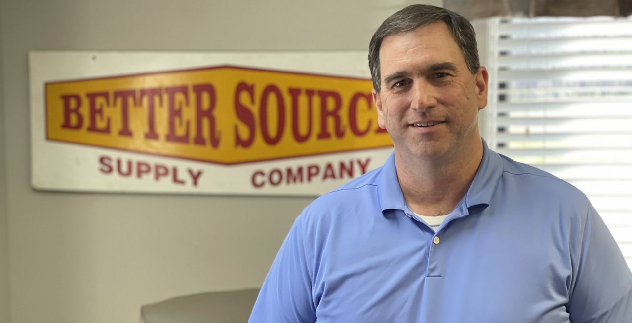 Robby Stadinger of Better Source Supply poses and smiles by his company's sign