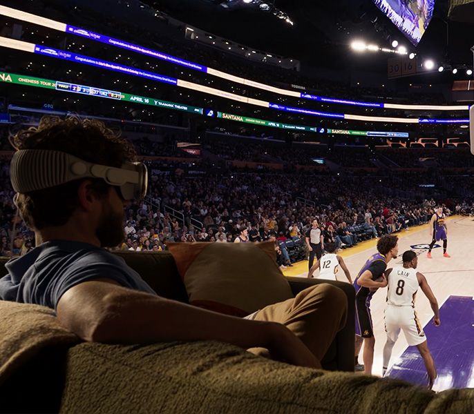A Lakers fan sitting in the stands with Apple immersive headset on