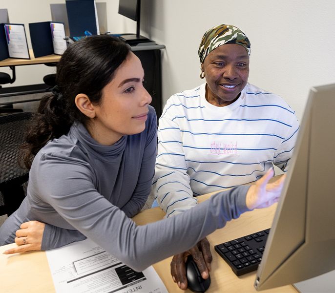 An adult female student getting instruction in a computer lab 