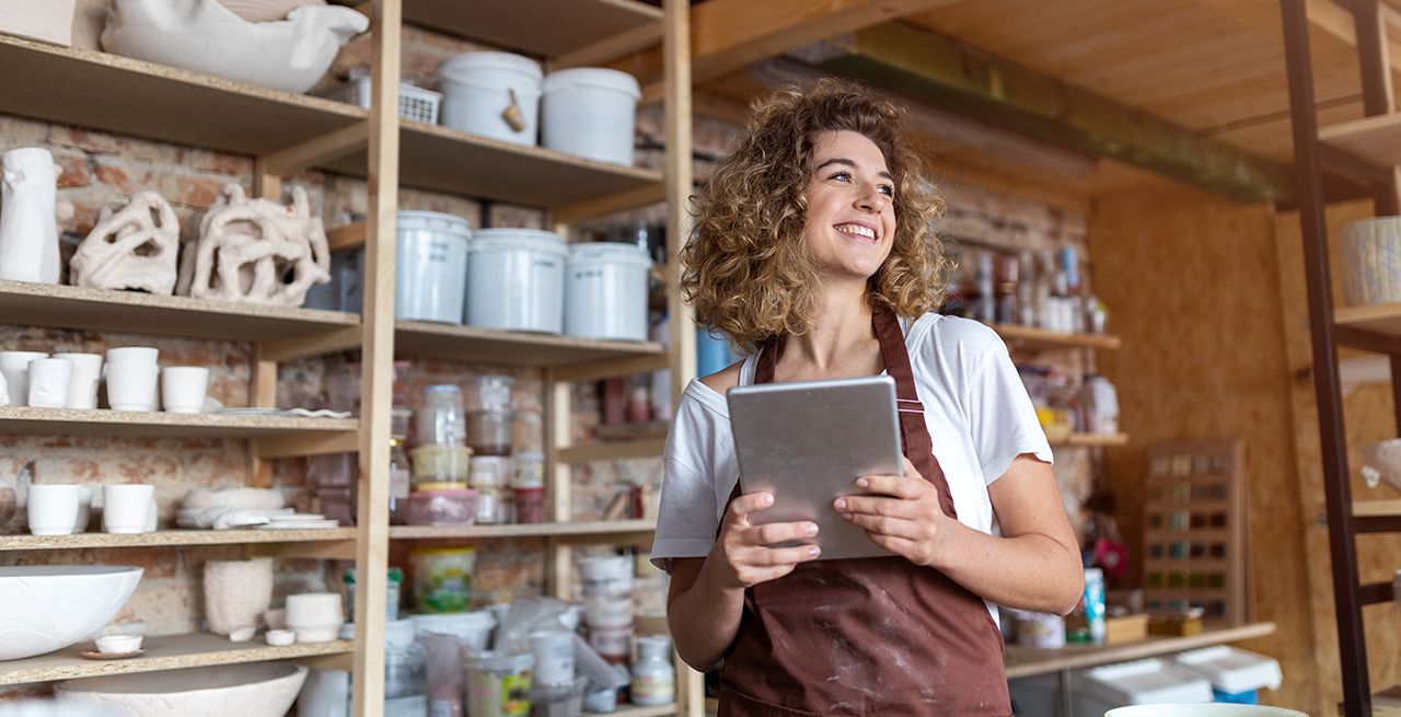 Small business owner in her store smiling holding tablet