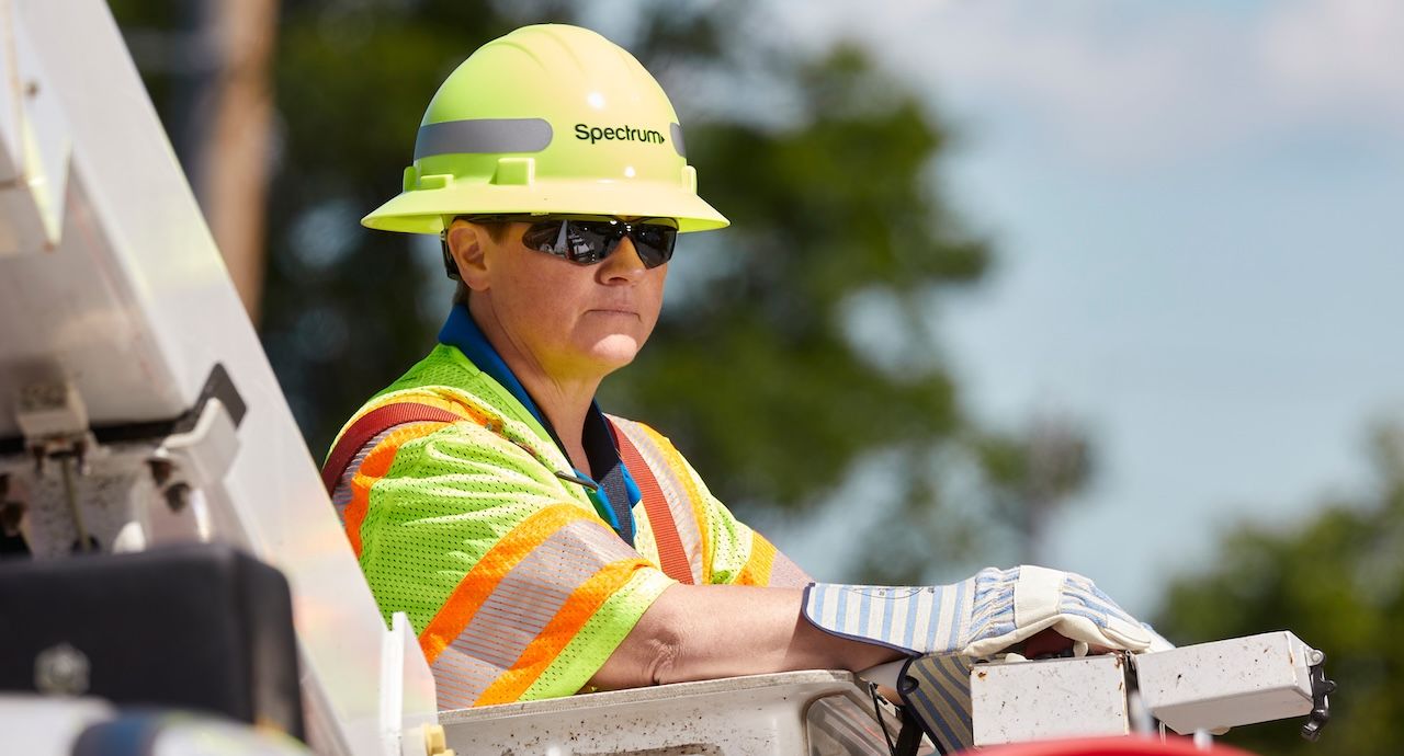 A female Spectrum field technician working in a bucket