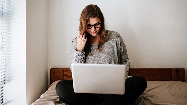 A woman using her laptop on her bed