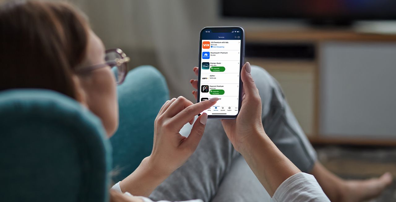 Woman using her phone in her living room to peruse Spectrum Seamless Entertainment content