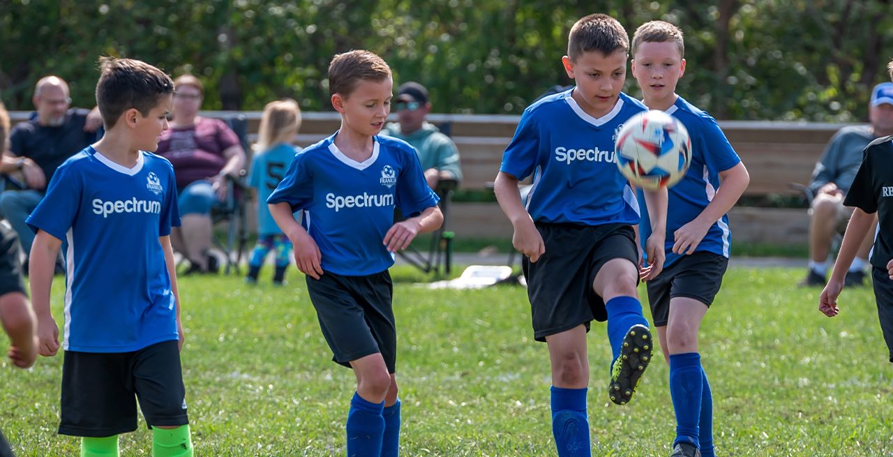 Children in uniforms playing team soccer on an outdoor field