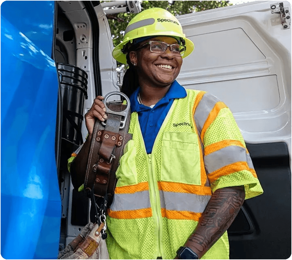 A Spectrum field technician standing at the back of her van, smiling