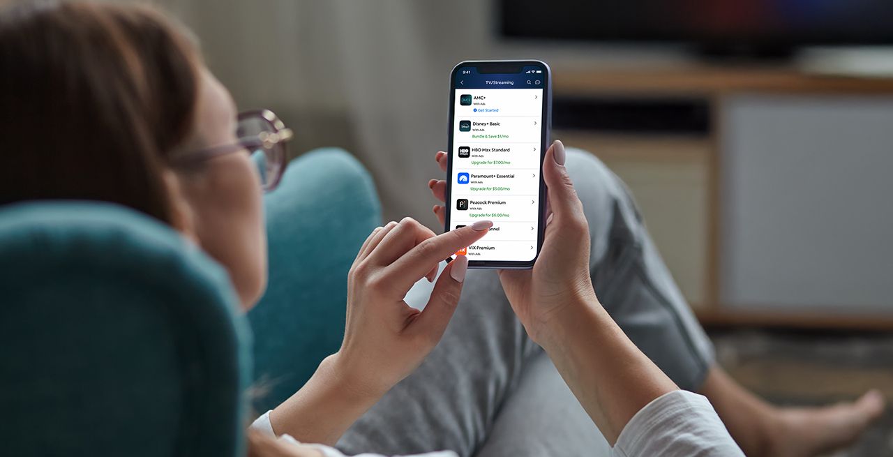 Woman using her phone in her living room to peruse Spectrum Seamless Entertainment content