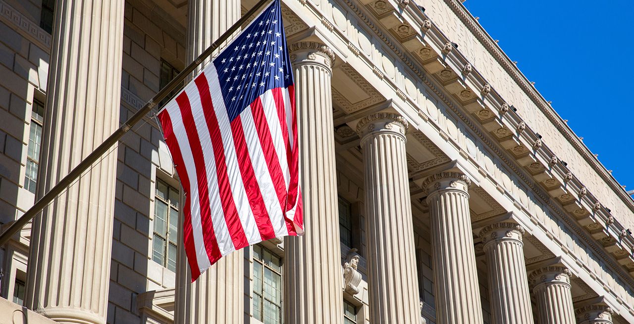 American flag hanging from a federal building with columns