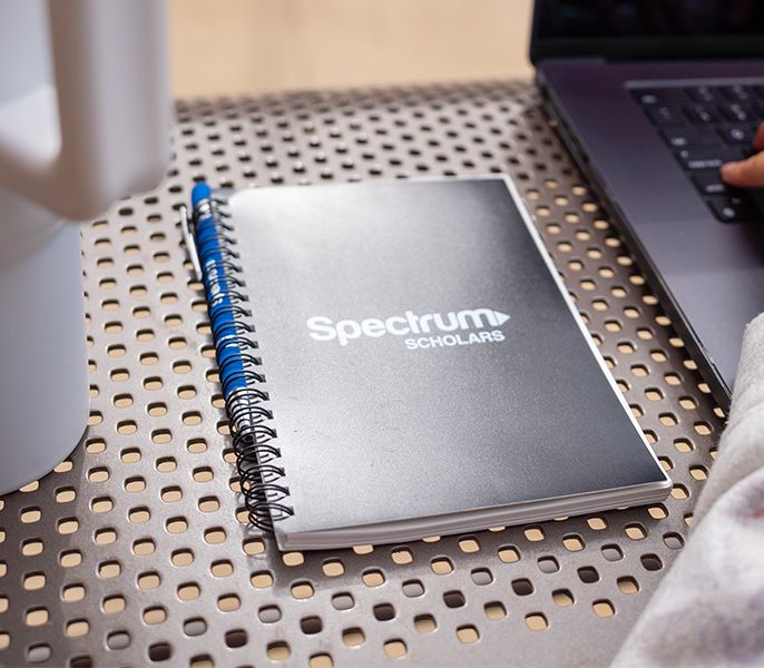 Spectrum-branded notebook sitting on a table with a laptop