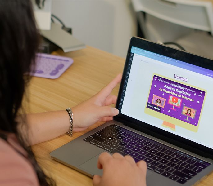 Person using a laptop viewed from over the shoulder, Latinitas website on screen