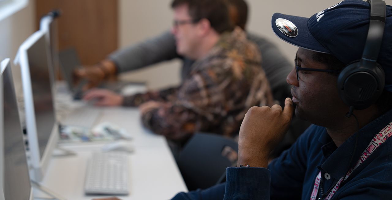 An adult student using a desktop computer in a computer lab