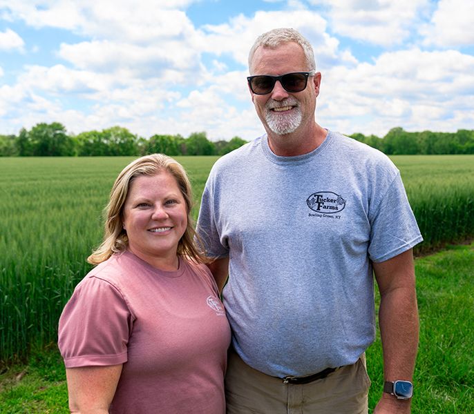 The owners of Tucker Family Farm pose by one of their grain fields
