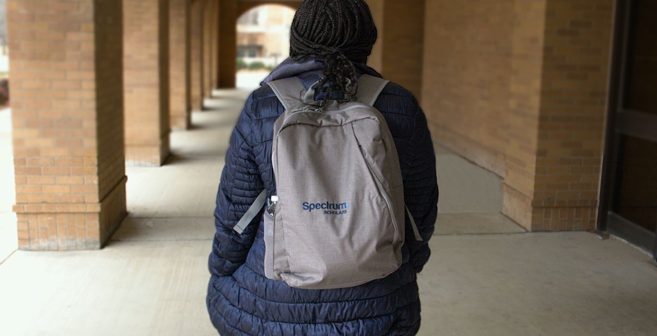 College student with backpack on walking through a campus breezeway