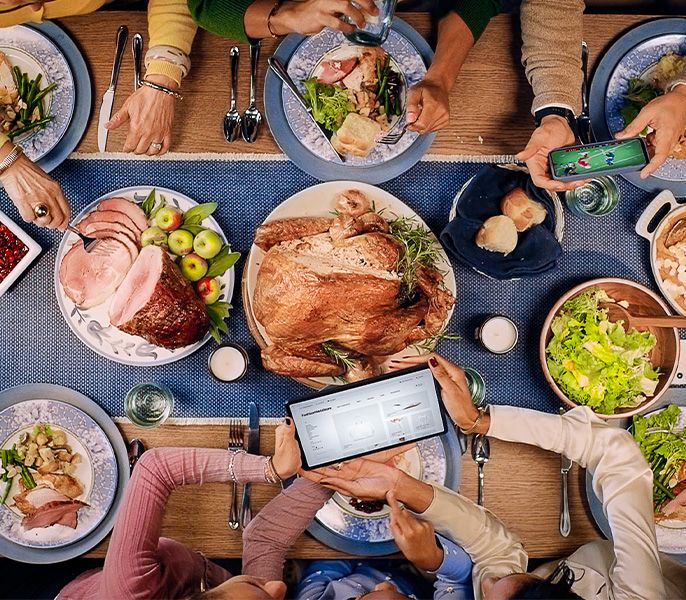 A Thanksgiving table with people using their devices