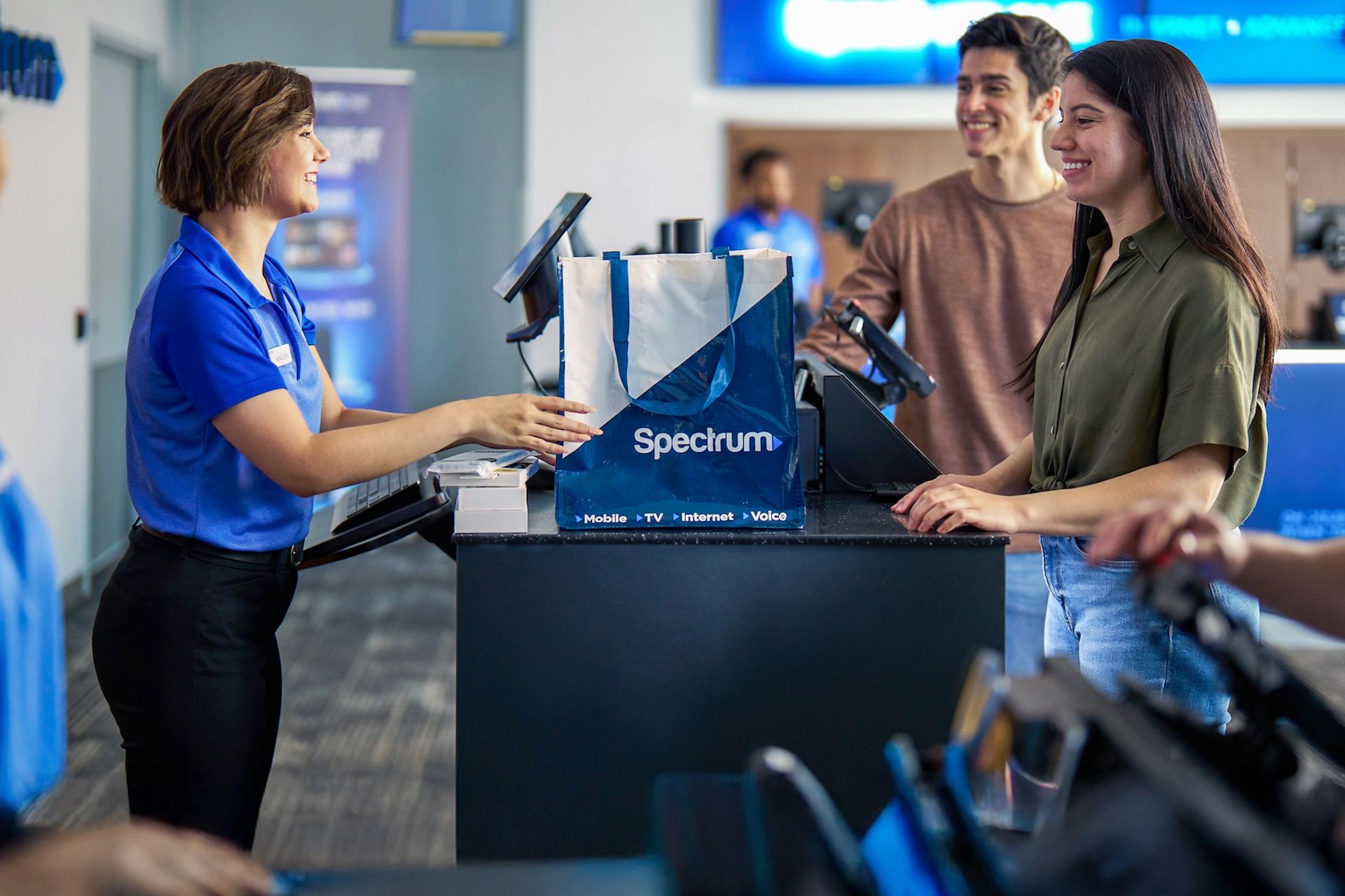 Spectrum Mobile store sales rep assisting smiling customers who are making a purchase