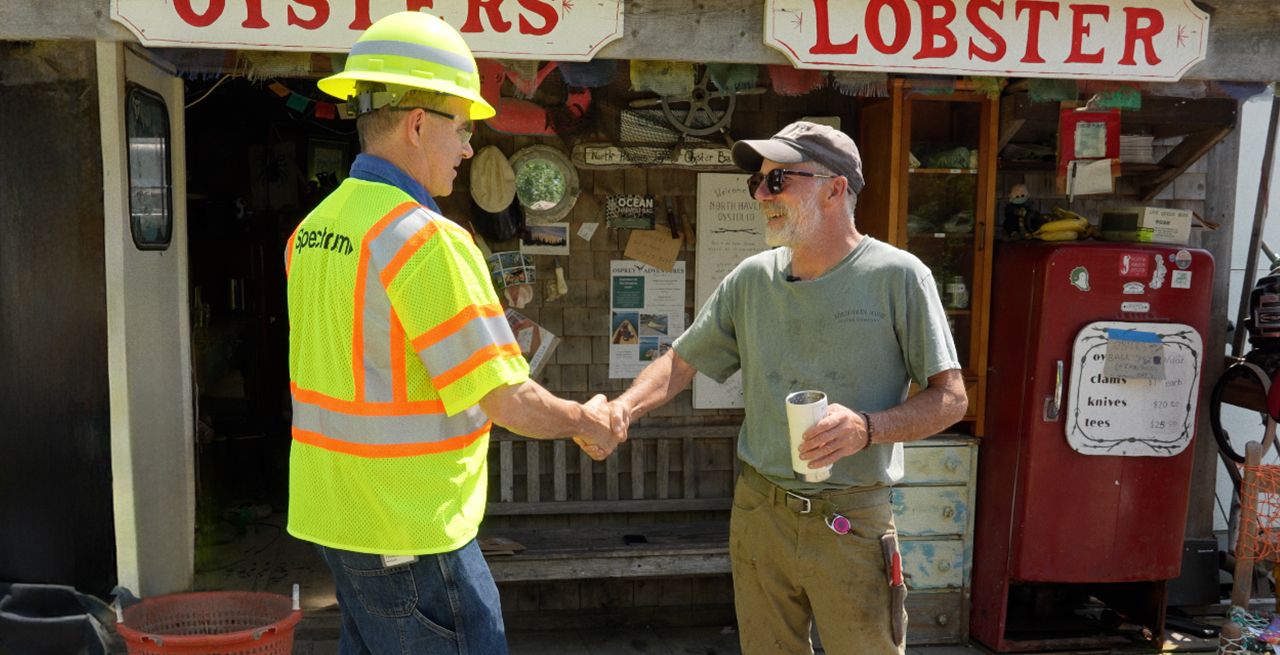 Spectrum technician and customer shaking hands in front of a lobster shack